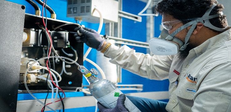 Technician wearing a respirator troubleshooting analyzer wiring
