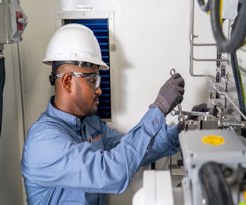 AIC technician in hard hat adjusting a field instrument during calibration